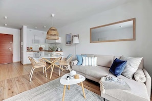 A modern living room with a sofa, coffee table, and dining area. - Waterlane F13 | Spa, Pool & Gym | Riverside (Gdańsk)
