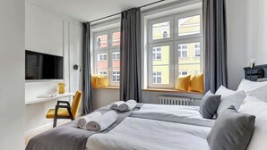 Ein Hotelzimmer mit Bett, Fernseher, Schreibtisch und einem Fenster mit Vorhängen.