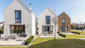 En moderne boligbygning med en patio, store vinduer og et minimalistisk design.