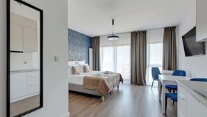 A modern hotel room with a bed, a desk, and a chair.