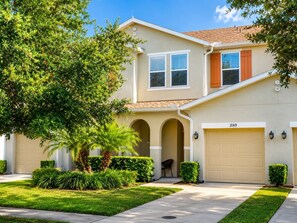 A two-story house with a garage, a covered porch, and a well-maintained lawn. - Townhome Close to Disney w Resort Pool (Kissimmee)