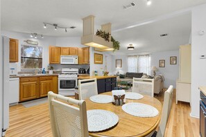 Una cocina moderna con armarios de madera, una isla central y un comedor con una mesa redonda y sillas.