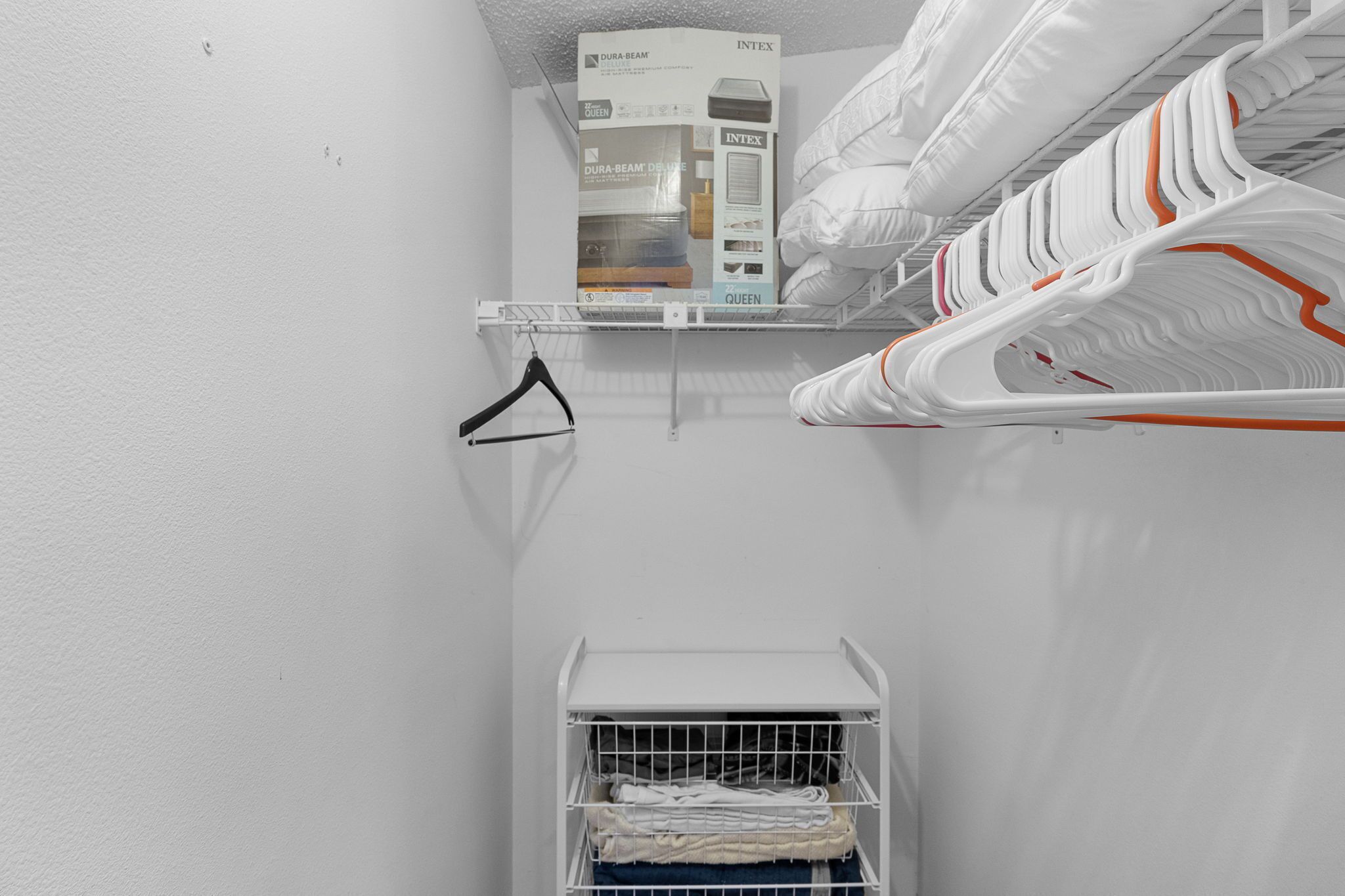 A storage closet with shelves, a hanging rack, and a cart.