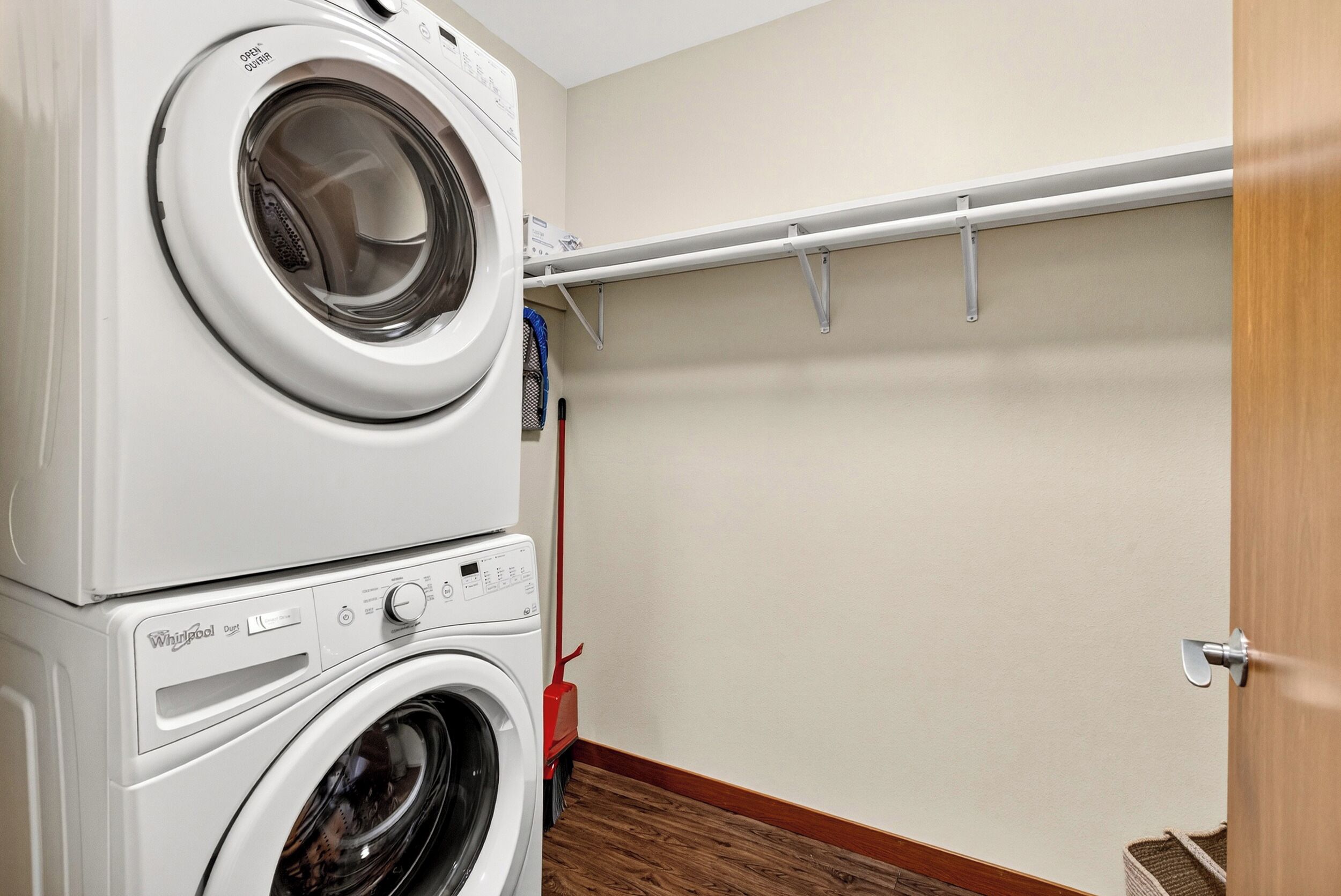 A laundry area with stacked washing machines and a drying rack.