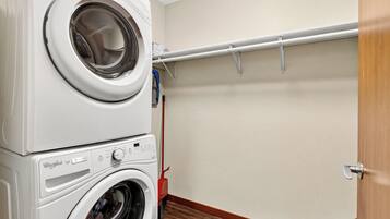 A laundry area with stacked washing machines and a drying rack.
