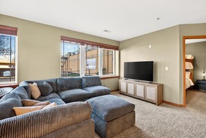 A living room with a sectional sofa, a flat-screen TV, and a cabinet. - Riverfront Retreat – 10 Mins to Lambeau! (Green Bay)
