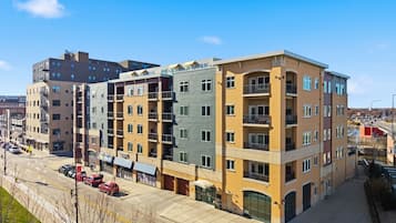 Un immeuble à plusieurs étages, avec un espace commercial au rez-de-chaussée, un parking et un ciel dégagé.