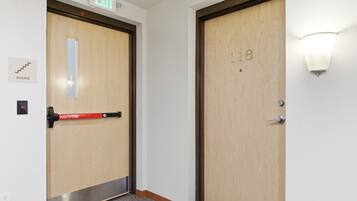 Two wooden doors with a push bar on the left, an exit sign above, and a stairway sign below.
