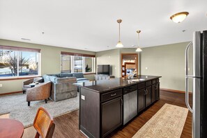 A modern kitchen with a central island, built-in appliances, and a dining area with a table and chairs. - Riverfront Retreat – 10 Mins to Lambeau! (Green Bay)