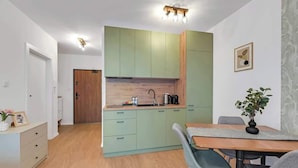 Una cucina compatta con mobili verde chiaro, un piano di lavoro in legno e un'area pranzo con tavolo e sedie.