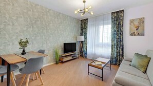 Un soggiorno moderno con un divano, un tavolo da pranzo con sedie, una TV e una lampada.