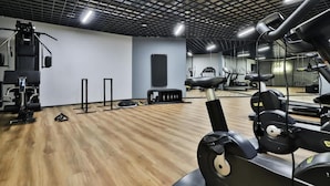 Una palestra con attrezzature per esercizi, uno specchio a parete e un pavimento in legno.