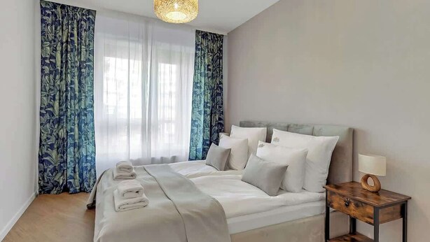 Una camera da letto con un letto, tende, un comodino e una lampada.