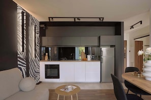 Eine moderne Küche mit Einbauofen, Kühlschrank und Essbereich mit Holztisch und Stühlen.
