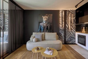 Ein modernes Wohnzimmer mit einer Couch, zwei Couchtischen, einer Wand mit Zebra-Muster und einem großen Gemälde.