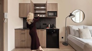 Ett modernt kök med mikrovågsugn, kaffebryggare och en person som sträcker sig efter en tallrik.
