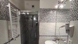 A bathroom with a shower, toilet, sink, and tiled walls.