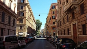 A street lined with parked cars and buildings with classical architecture.