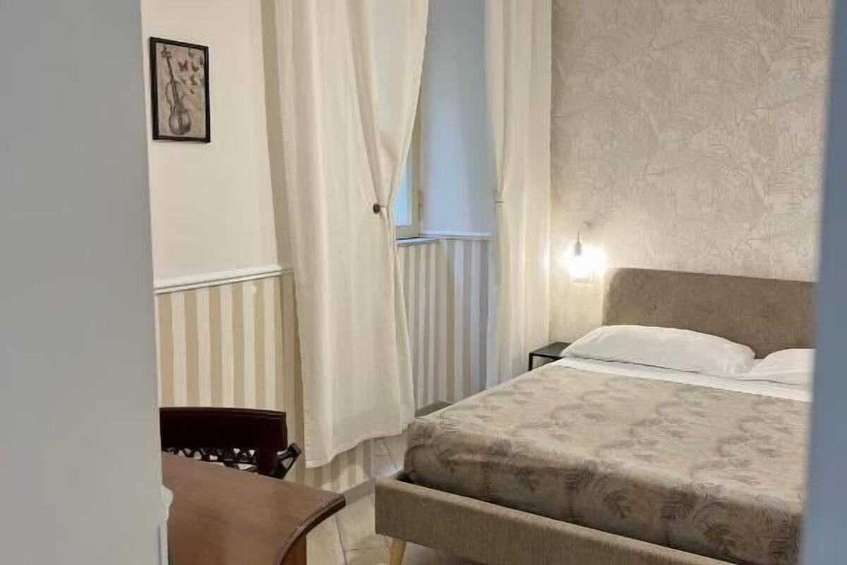 Un dormitorio con cama, escritorio, silla y lámpara colgante.