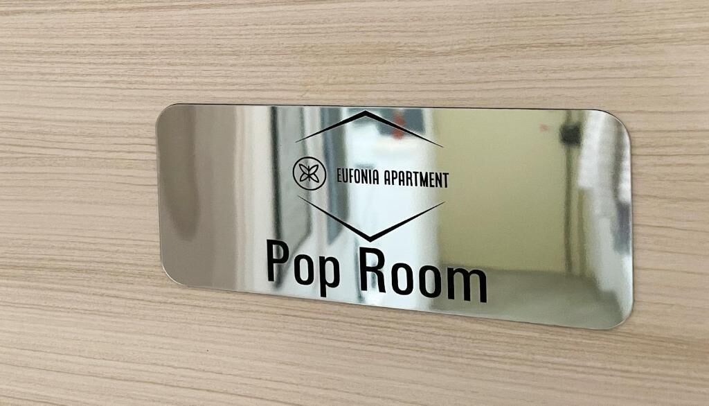 A metallic sign with 'EUFONIA APARTMENT Pop Room' text, a logo, and a diamond shape.