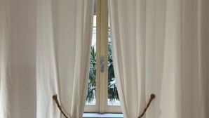 A window with white curtains and a radiator below it.