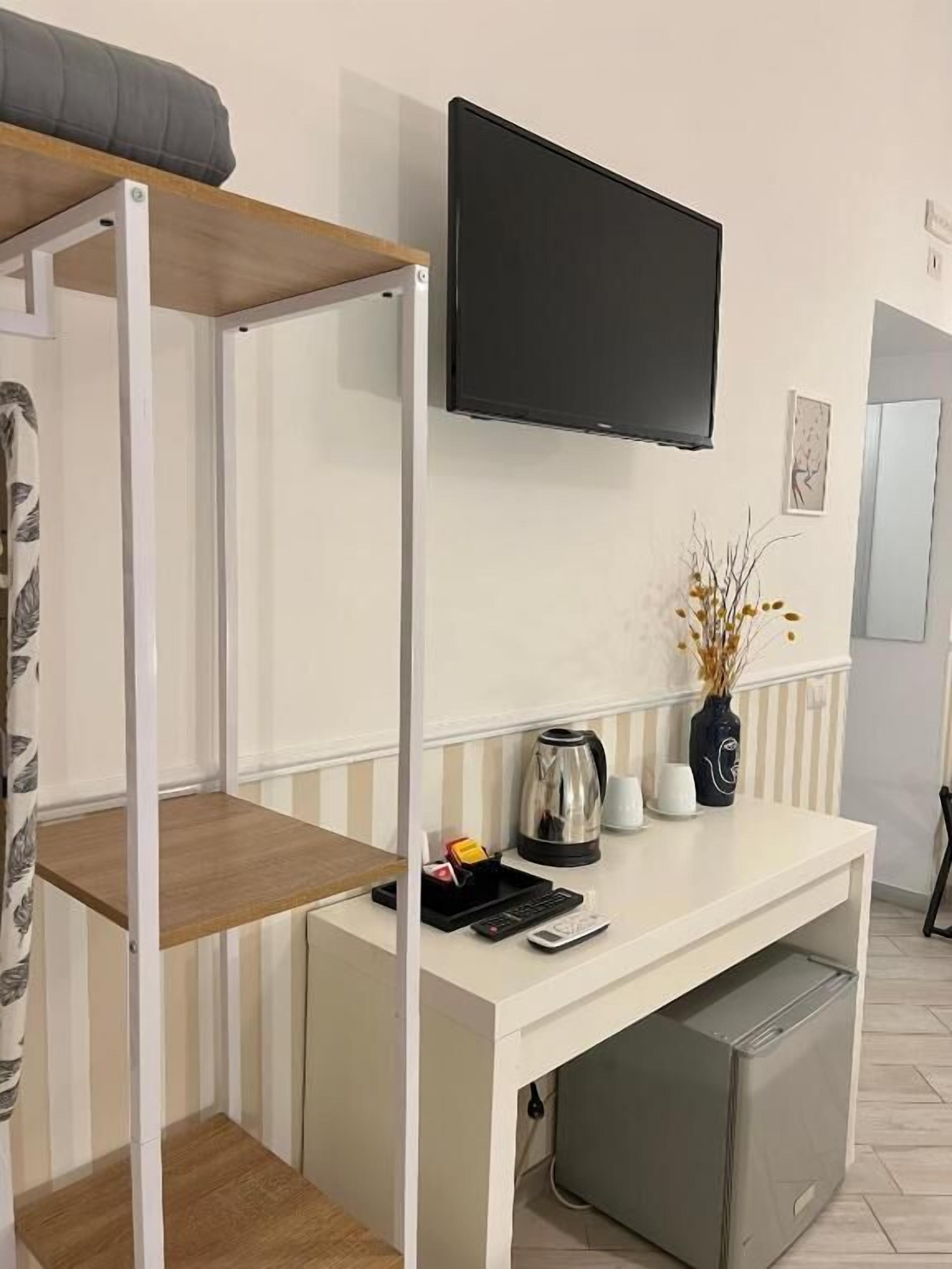Une chambre compacte comprenant un lit superposé, un petit bureau avec un téléviseur à écran plat, une bouilloire et une machine à café.