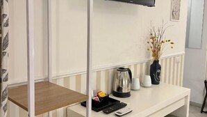A compact room with a bunk bed, a small desk with a flat-screen TV, a kettle, and a coffee maker.