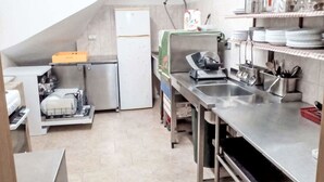 Eine Küche mit Edelstahlgeräten, einer Geschirrspülstation und Regalen mit Geschirr und Besteck.