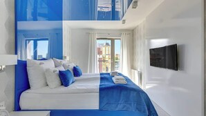 Ein modernes Hotelzimmer mit einem großen Bett, einem Fernseher und Blick auf die Stadt.