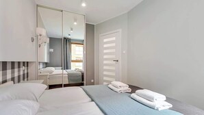 A hotel room with a bed, a mirror, a wardrobe, and a door. - Aura 99B | Riverside | City Center (Gdańsk)