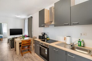 A modern kitchen with a dining area, a TV, and a window with curtains.