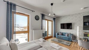 A modern hotel room with a large bed, a sofa, a TV, and a view of the outside. - Nadmotławie 83 | Riverside | Sauna & Gym (Gdańsk)