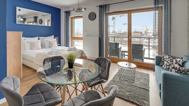 A modern bedroom with a bed, a glass dining table, and a sofa. - Nadmotławie 83 | Riverside | Sauna & Gym (Gdańsk)