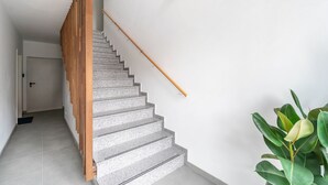 A staircase with a wooden handrail and a wall-mounted light fixture.