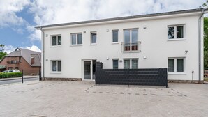 A two-story building with a flat roof, multiple windows, and a gated entrance.