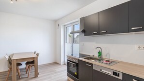 A modern kitchen with dark cabinets, a stainless steel sink, and a wooden dining table.