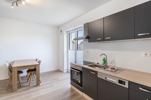 Een koffiezetapparaat/waterkoker, een koelkast, een oven, een kookplaat