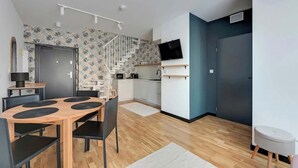 Eine moderne Wohnung mit Essbereich, Küche, Treppe und einem an der Wand befestigten Fernseher.