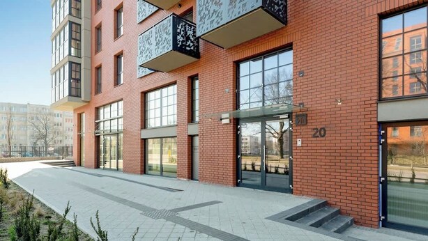 Ein modernes Gebäude mit großen Fenstern, einer Ziegelaußenwand und der Nummer 20.