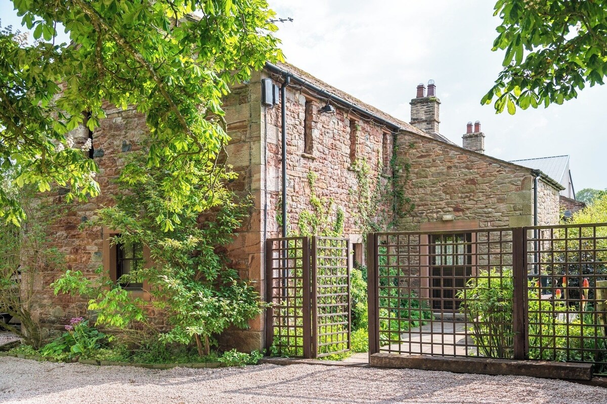 A stone building with a gravel driveway and a metal gate.
