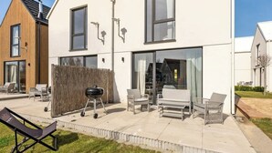 Et moderne hus med terrasse, havemøbler og grill.
