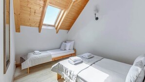 A room with two beds, wooden ceiling beams, a skylight, and a white wall. - Dębki 5 | Rodzinny Apartament | Nad Morzem (Dębki)