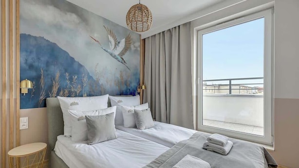 Ein Hotelzimmer mit einem großen Bett, Blick auf die Stadt und einem Wandgemälde.