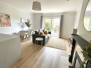 A modern living room with a sofa, dining table, and a large window. - Luxury By The Coast 6 (Galway)