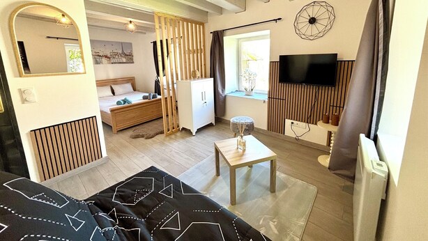 Una habitación moderna con una cama, televisión, una mesita y una ventana.
