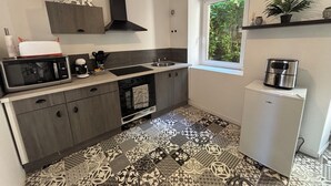 Una cocina compacta con microondas, tostadora, fregadero y un refrigerador pequeño.