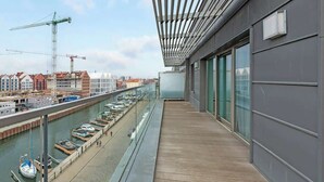 Un balcón con vista a un canal, una grúa de construcción y edificios al fondo.