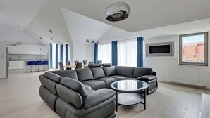 Una sala de estar moderna con un sofá seccional, una mesa de centro redonda y un televisor montado en la pared.