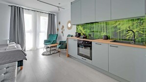 A modern kitchen with grey cabinets, a built-in stove, and a large fish tank. - Aura IV 25 | City Center | near Gdansk Shipyard (Gdańsk)