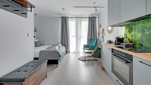 A modern bedroom with a bed, bedside table, and a desk area with a chair. - Aura IV 25 | City Center | near Gdansk Shipyard (Gdańsk)